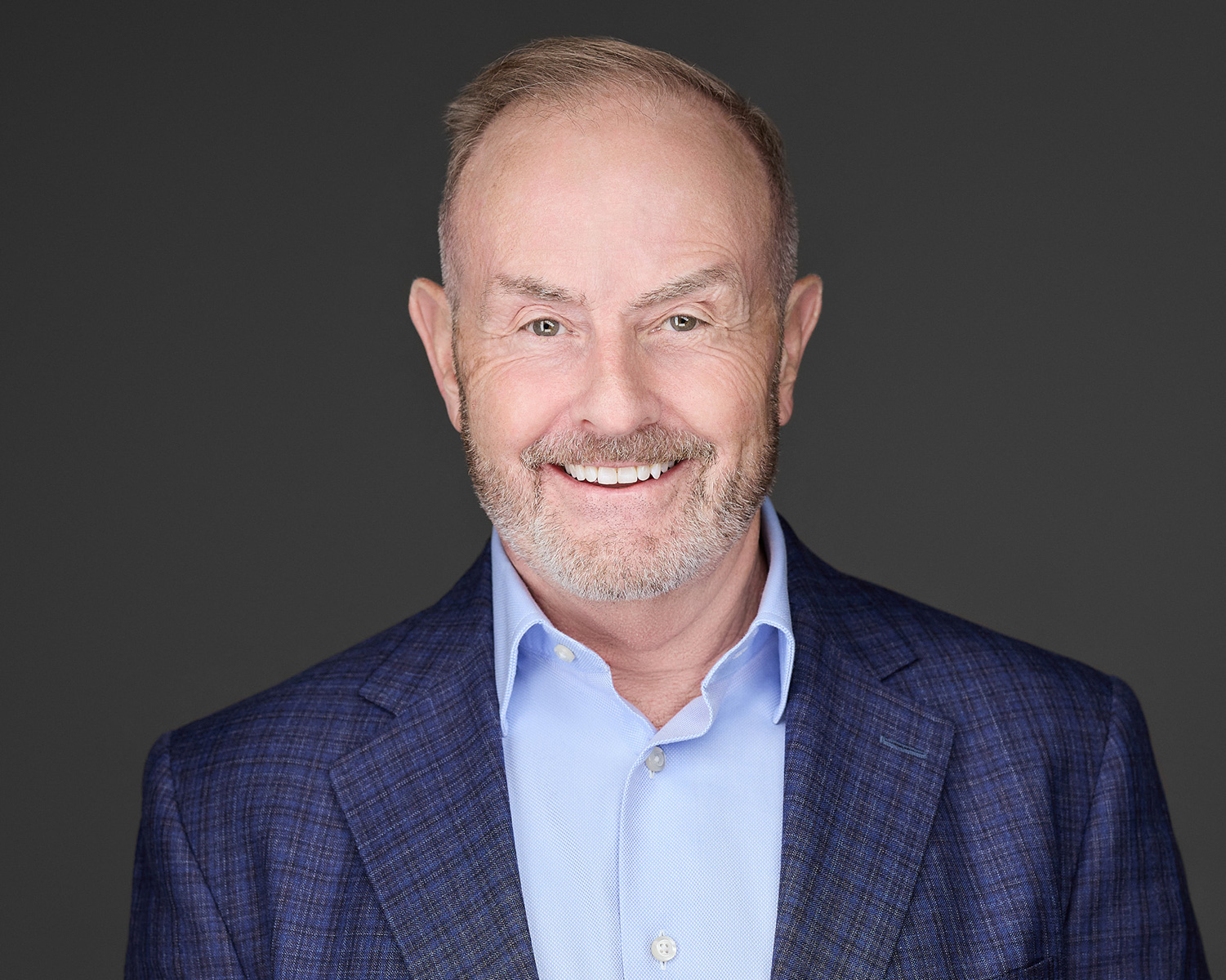 Professional headshot of Bob Affleck in blue jacket – Dental Coach USA Bob Affleck, Co-Founder and CSO of Dental Coach USA, smiling in a professional headshot while wearing a blue blazer and light blue shirt against a dark background – Dental Coach USA